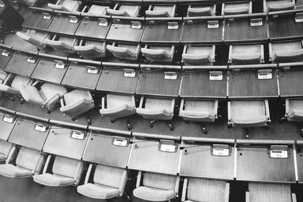 Rows of empty seats and wooden desks curve around an auditorium in a tiered arrangement