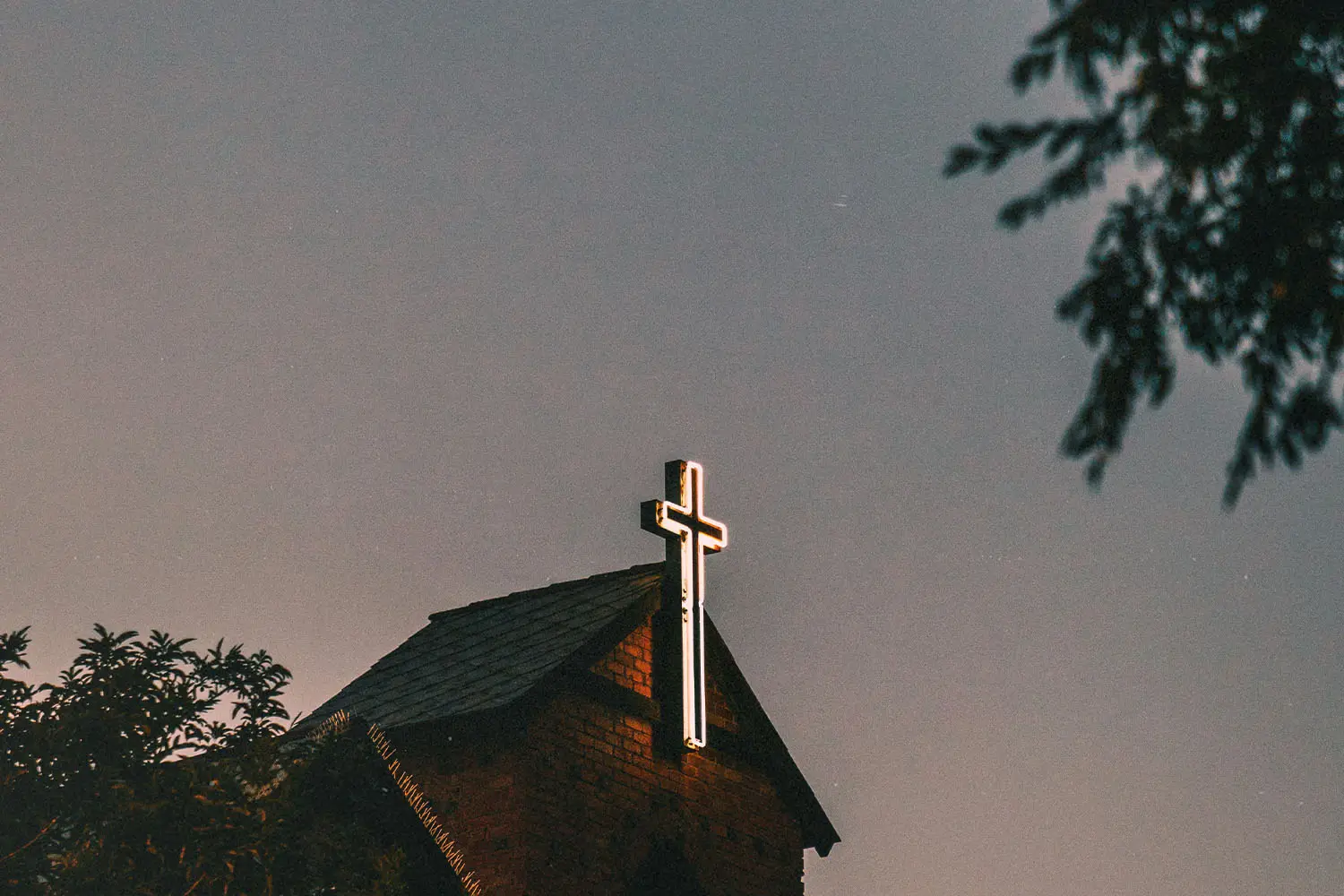 Neon white cross on the front of building roof