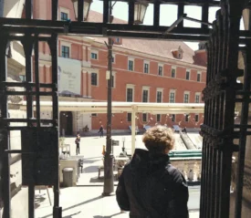 man exiting a iron gate into a courtyard