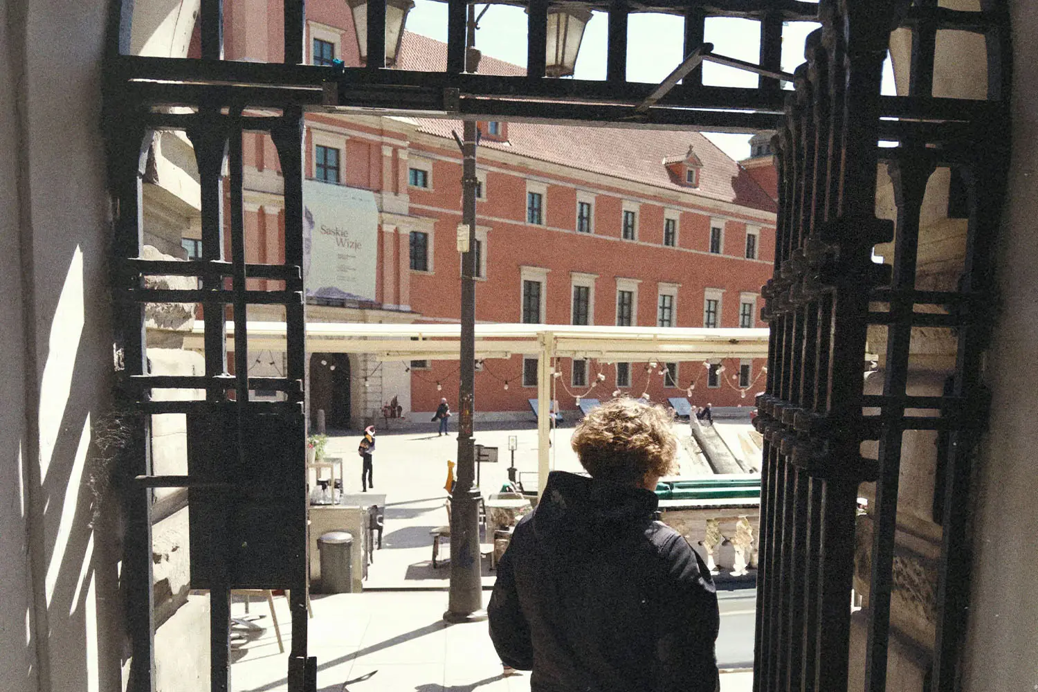 man exiting a iron gate into a courtyard