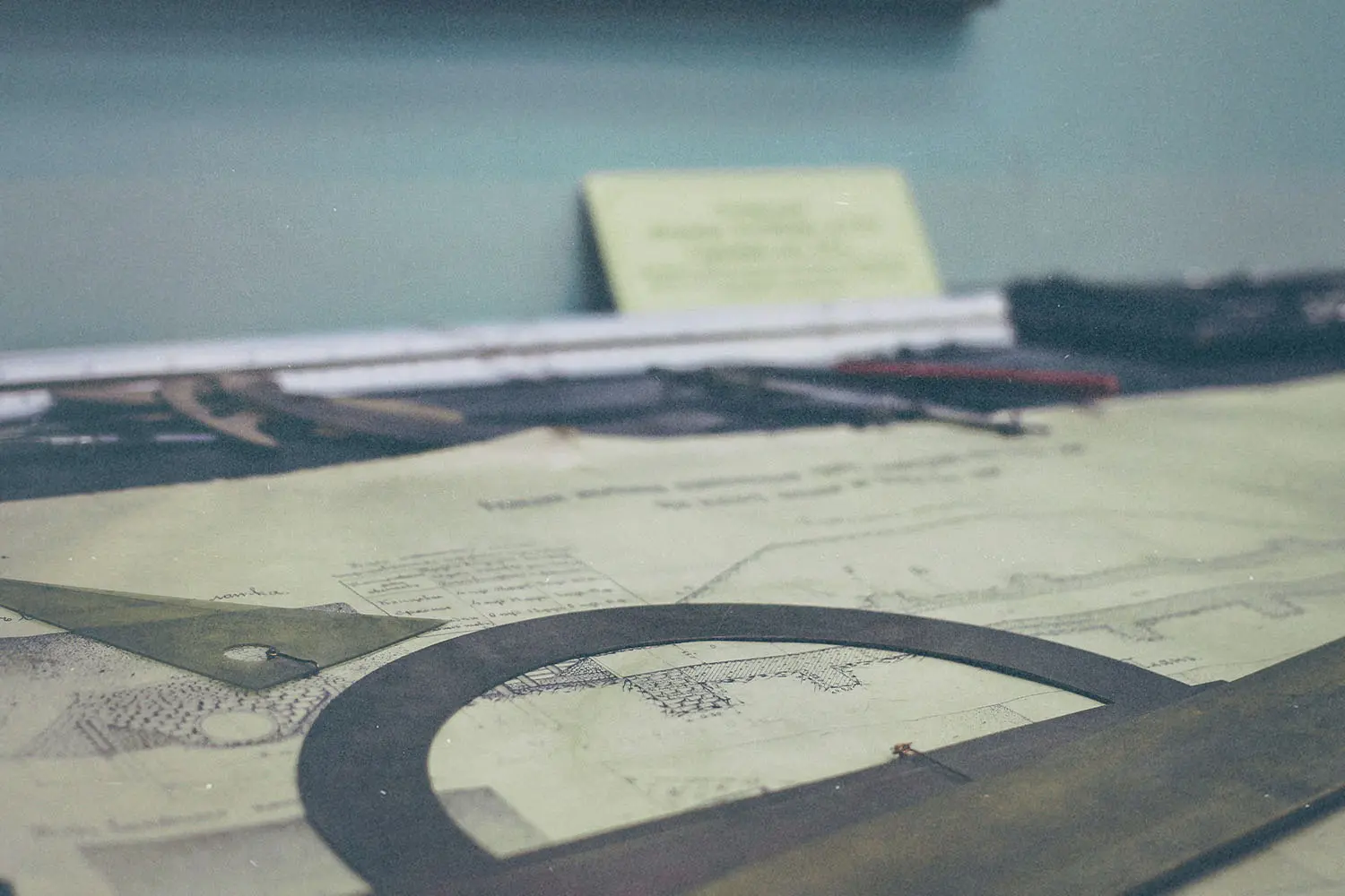 A drafting table with architectural drawings, rulers, and measuring tools arranged across the surface