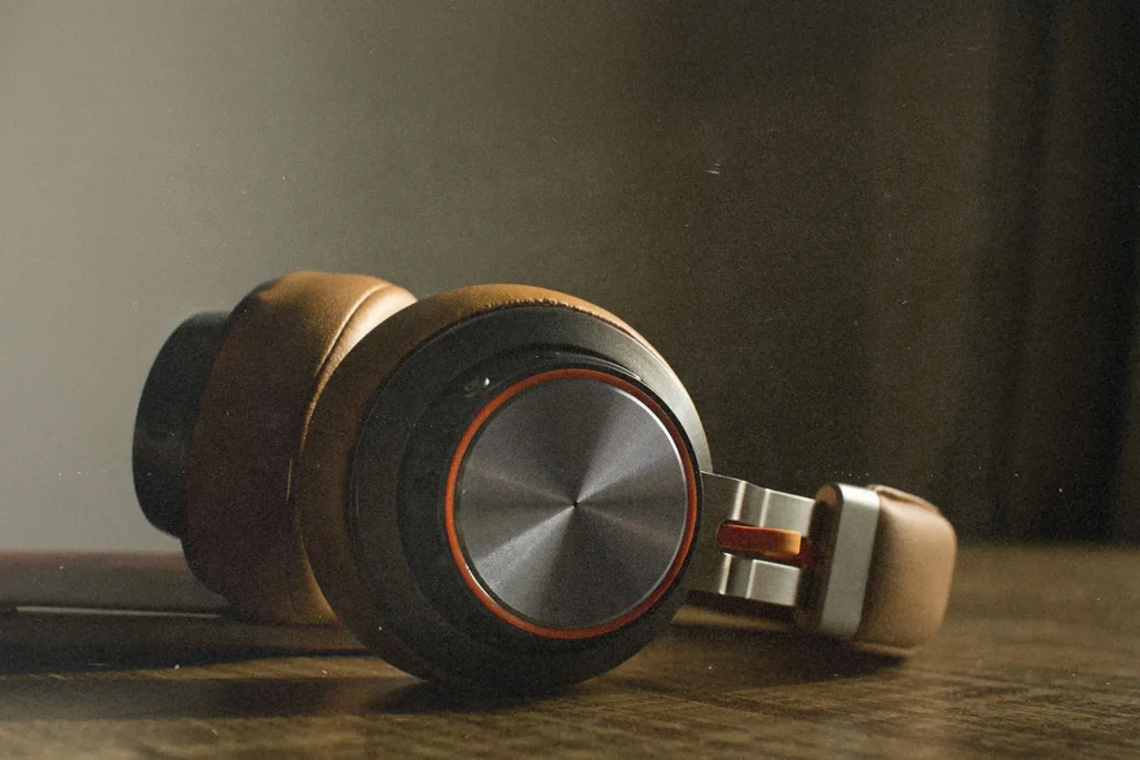 Close-up of brown over‑ear headphones resting on a wooden surface in soft, warm light