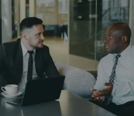 two business men talking at a desk in an office