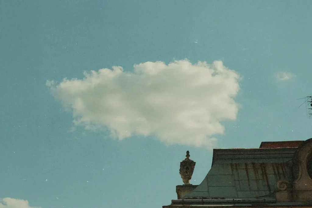 Single cloud in the sky behind building roof