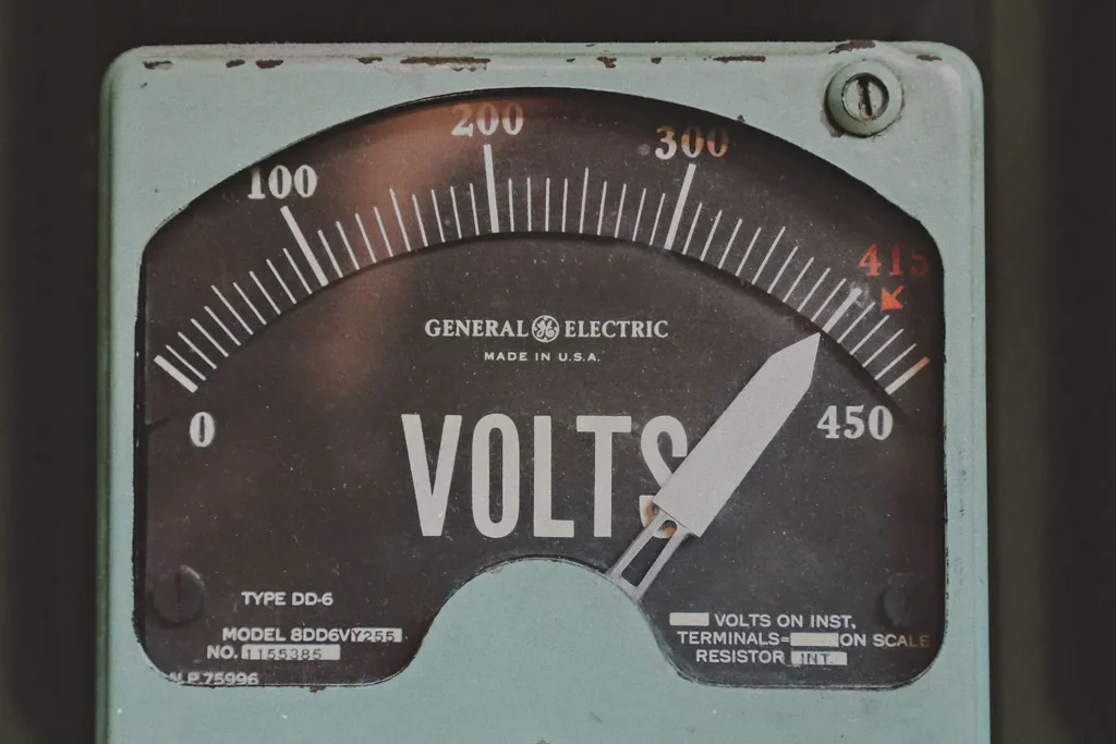 Close-up of an analog General Electric voltmeter with a needle pointing near 415 volts
