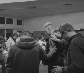 Group of people huddled , laying hands on each other, and praying