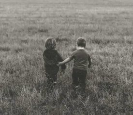 Two kids walking through a field