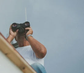 guy on roof looking through binoculars
