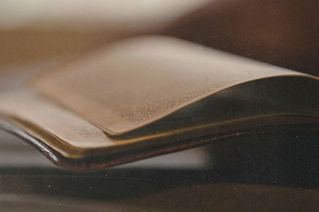 lose-up of an open Bible with softly curved pages, shown in warm, low light
