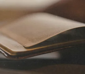 lose-up of an open Bible with softly curved pages, shown in warm, low light