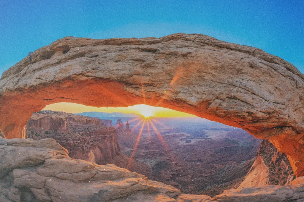 Canyon Landscape with the sun setting on the horizon. The sun is under a rock archway