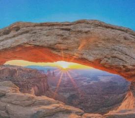 Canyon Landscape with the sun setting on the horizon. The sun is under a rock archway
