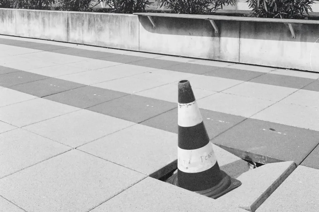 caution cone in a broken block of pavement