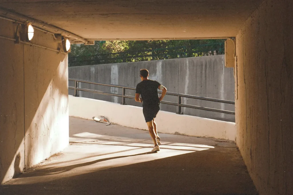 man wearing headphones jogging up a parking ramp