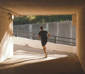 man wearing headphones jogging up a parking ramp