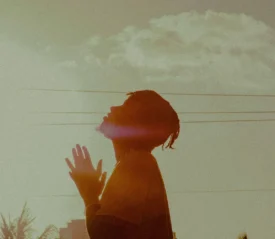 man's silhouette gazing up to the sky praying