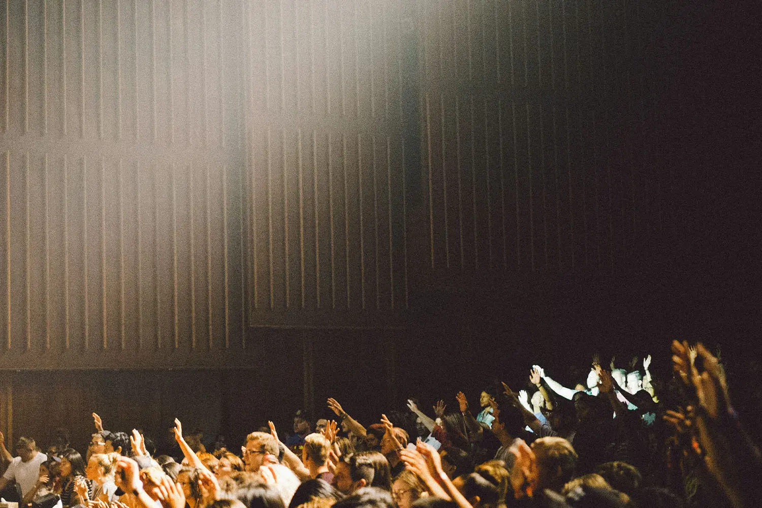 crowd of people with their hands raised in worship