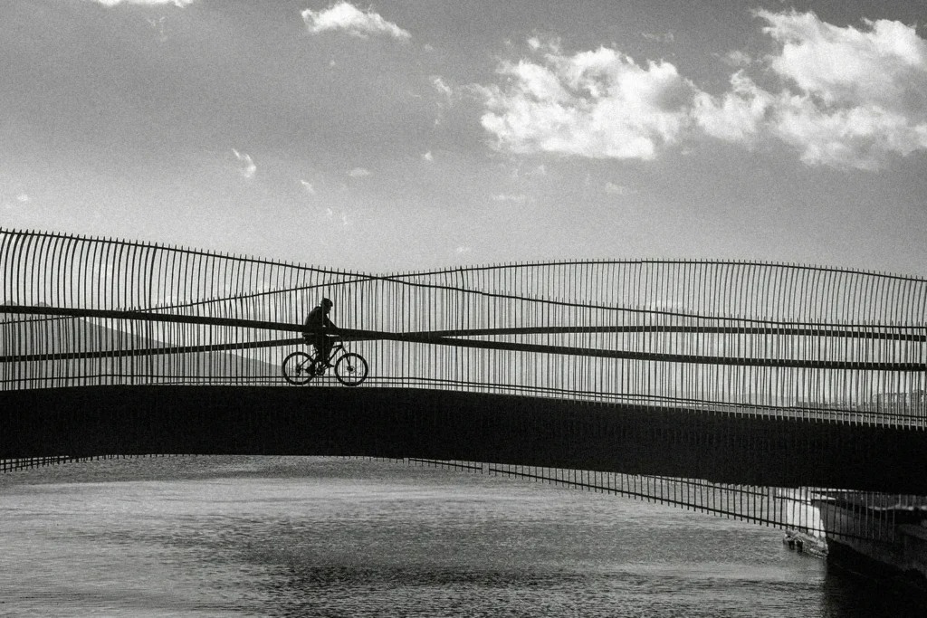 person on a bike riding over a bridge with water underneath