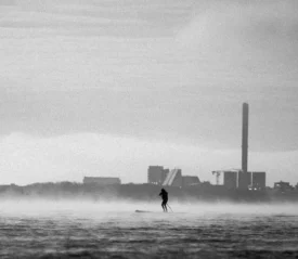 Person standup paddle boarding in the middle of rushing waters