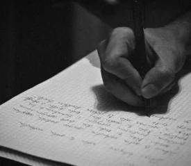 Hand holding a pen writing cursive in a notebook