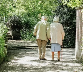 old couple holding hands walking through a garden