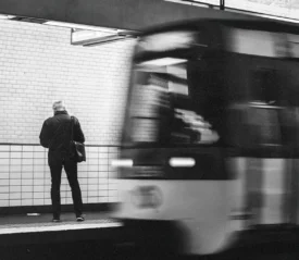 Person standing on a subway platform as a train speeds past in motion blur