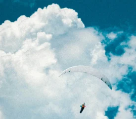 Person with parachute in the clouds
