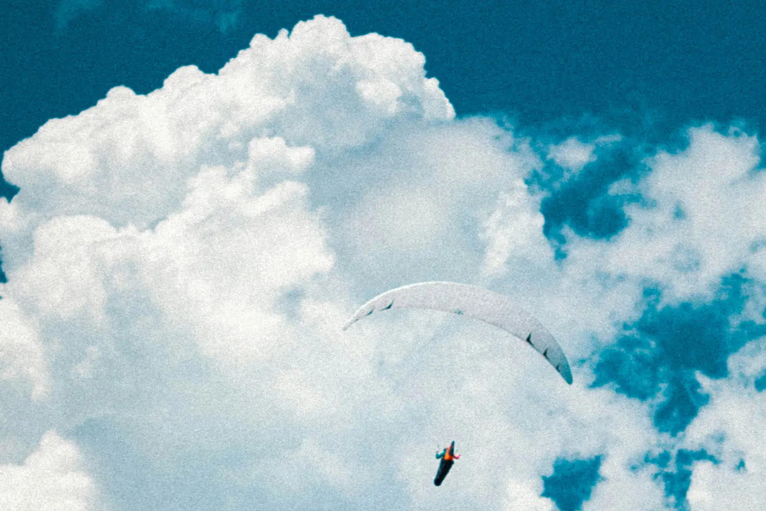 Person with parachute in the clouds