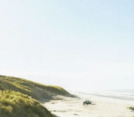 Ocean shores with grassy sand dunes and a pickup truck