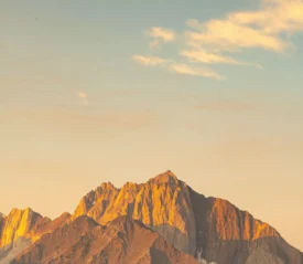 Sunrise casting warm hues across rugged mountain tops under a pale sky