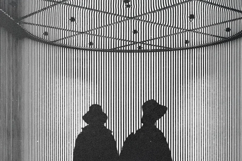 Silhouettes of two people standing beneath a striped, geometric installation with dramatic lighting