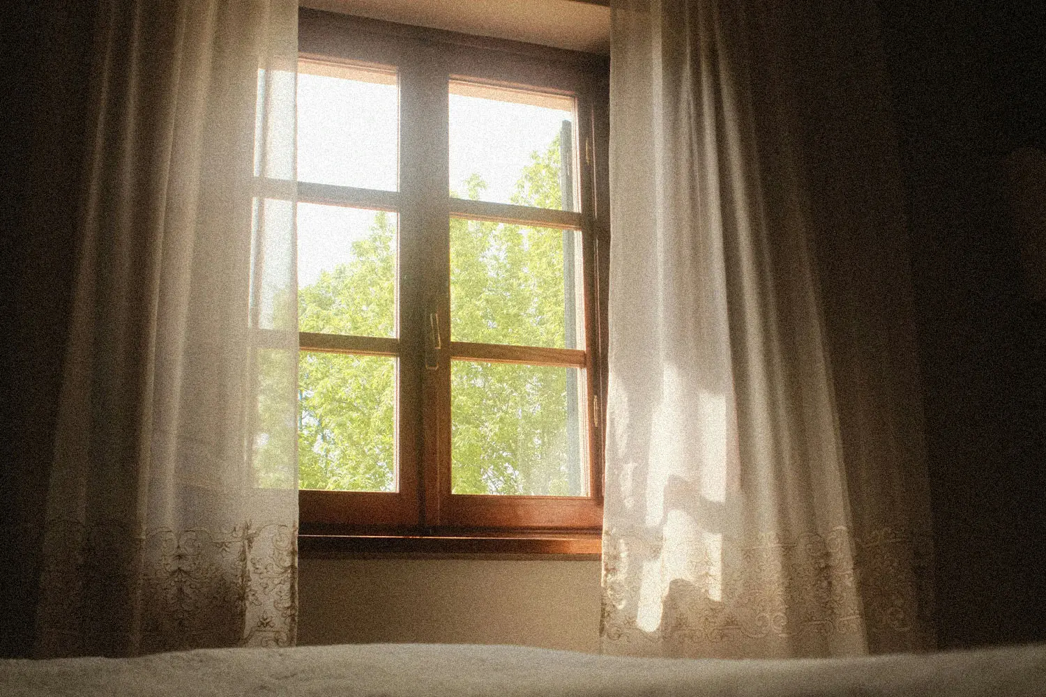 Sunlight shining through window with white curtains flowing in the wind