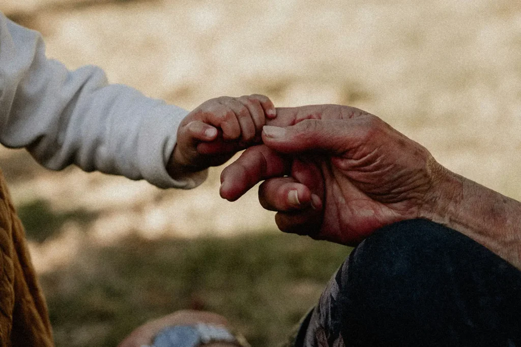 child's hand holding an elderly finger