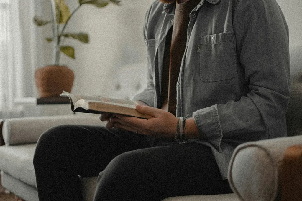 Man sitting on couch reading a Bible