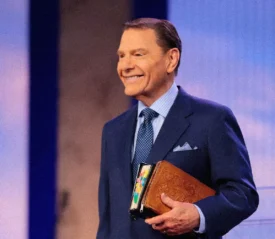 Kenneth Copeland smiling holding his Bible under his arm