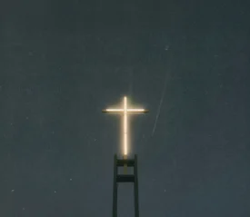Bright neon cross shining in a dark sky