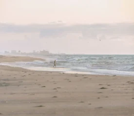 Person walking on ocean shore with high tide coming in