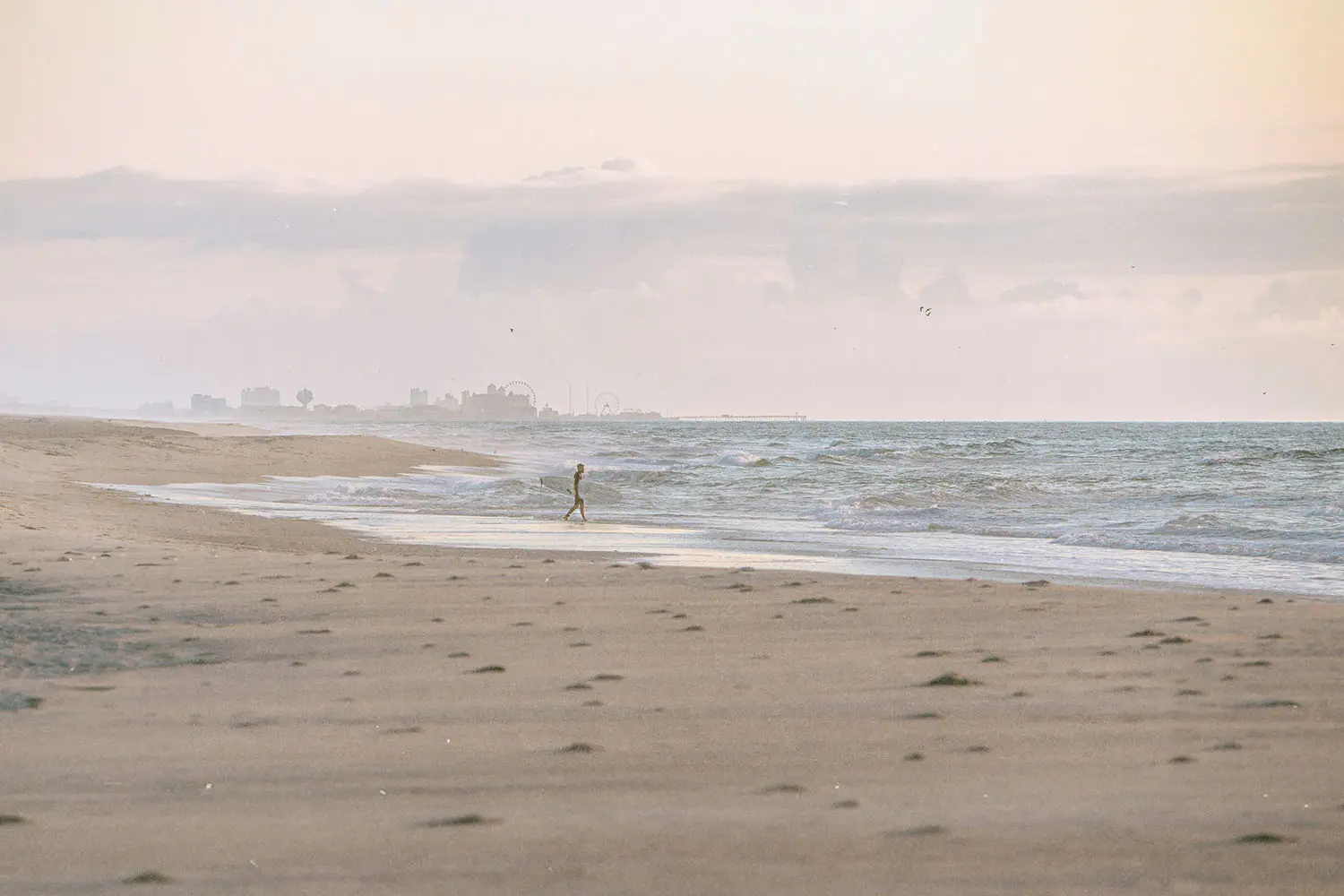 Person walking on ocean shore with high tide coming in