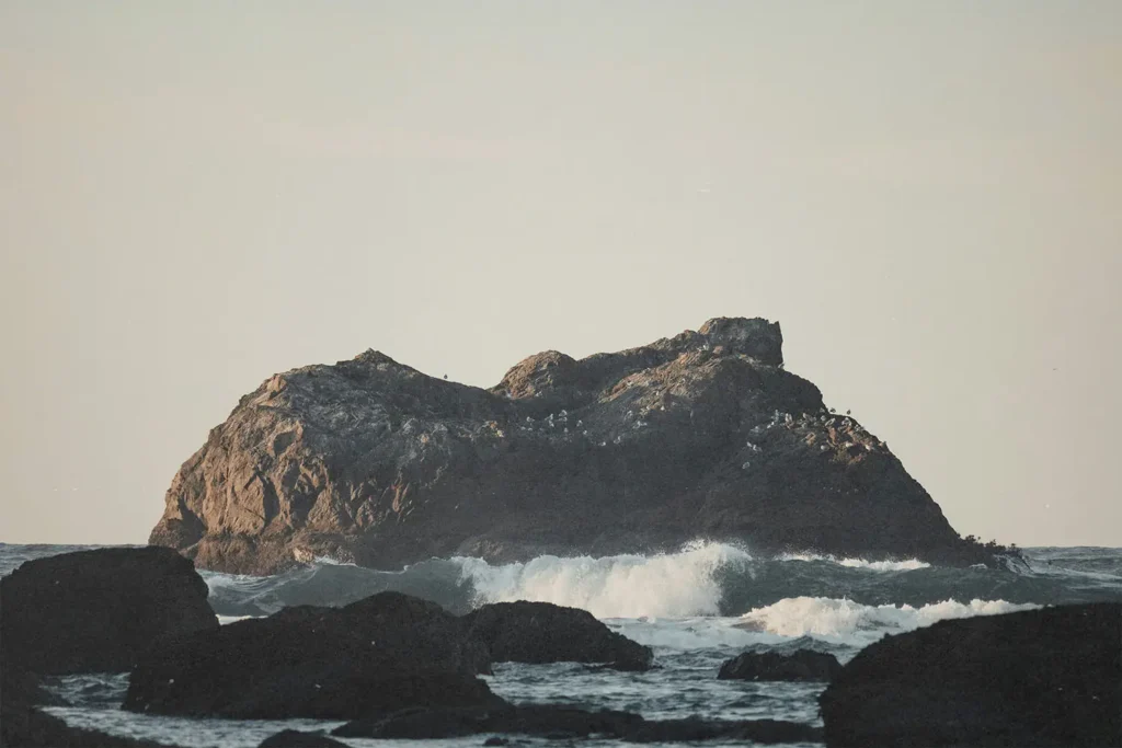 big rock sticking out of rough ocean