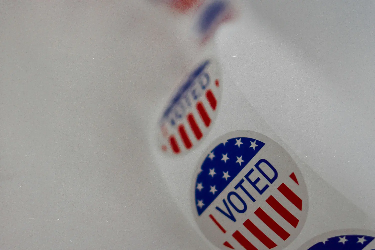 A strip of “I Voted” stickers featuring stars and stripes lies on a white surface