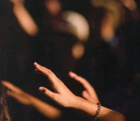 Light highlighting reached hands with shadows in the background