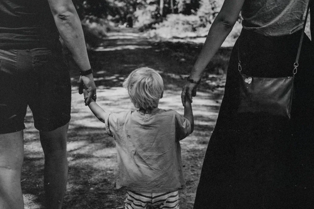 Little boy standing in the middle of his parents while holding their hands