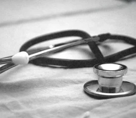 Stethoscope resting on a fabric surface in a soft, black‑and‑white medical-themed image