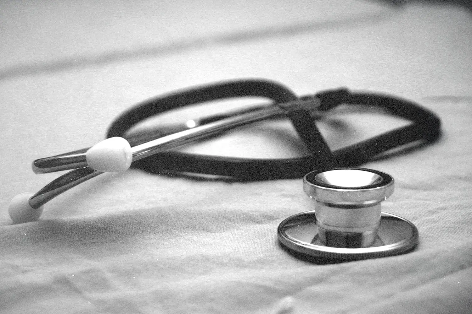 Stethoscope resting on a fabric surface in a soft, black‑and‑white medical-themed image