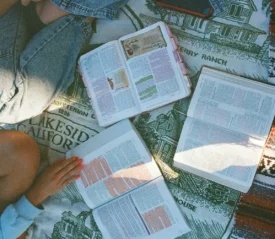 Group of 3 people sitting crisscross with Bibles open on the floor