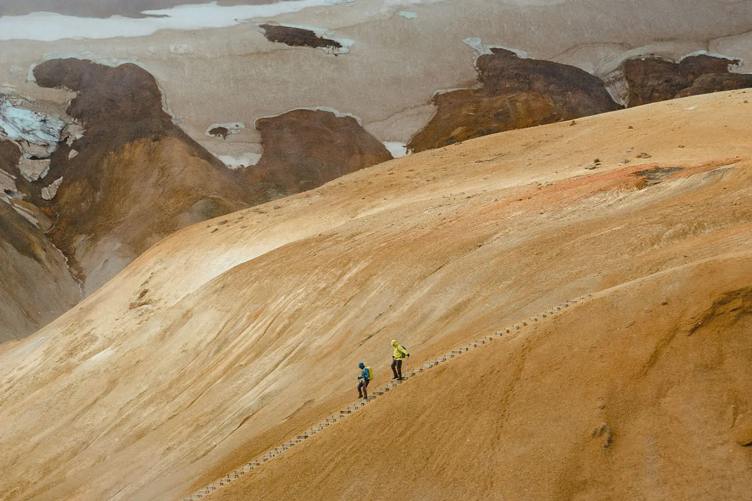 Two people walking down steps in a dessert sand dune