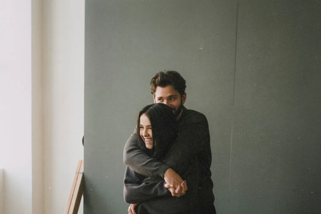 Man hugging a woman from behind as she smiles