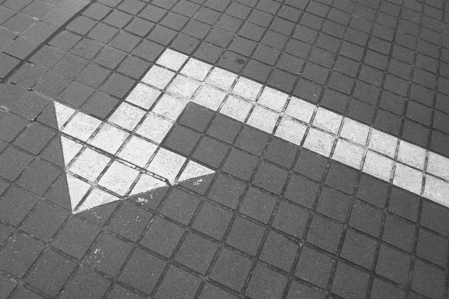 Painted arrow on sidewalk pointing left