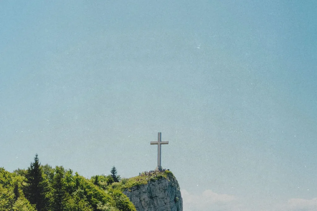 Stone cross on the edge of a rock cliff with clear skies in the background
