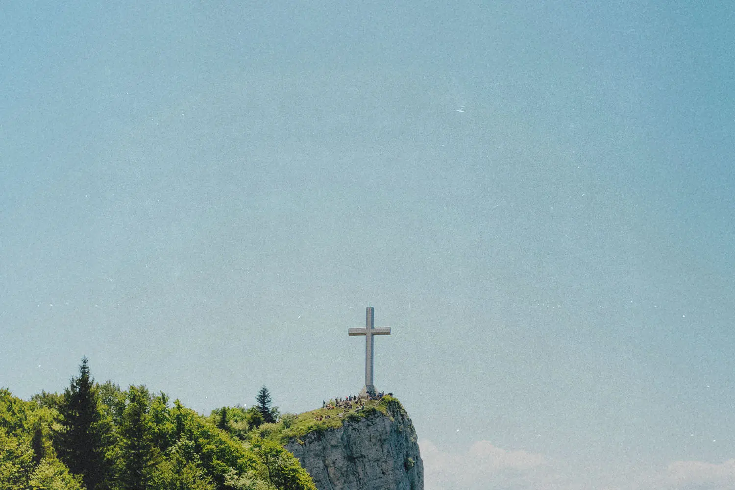 Stone cross on the edge of a rock cliff with clear skies in the background